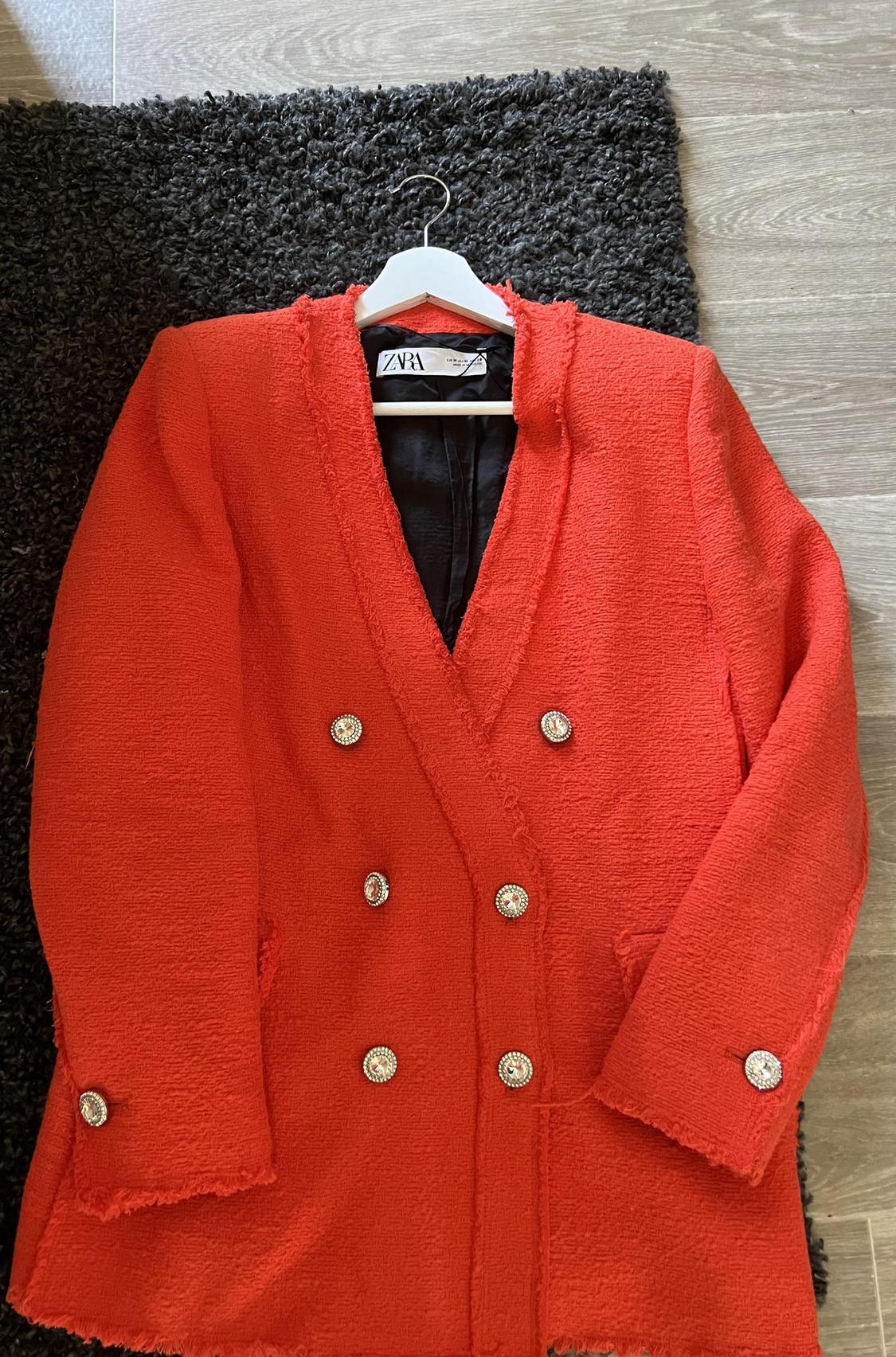 Front view of red jacket with shiny buttons and a rough texture.