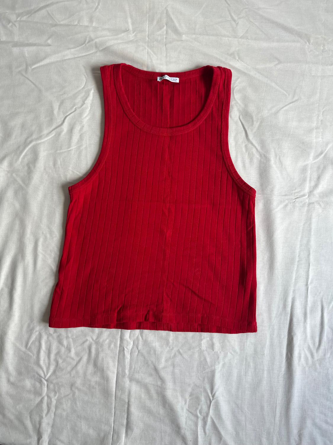 Red ribbed vest with a crew neck, laid out on a crumpled white fabric.