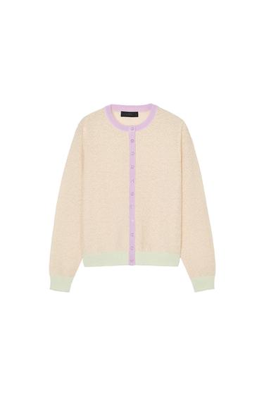 Front view of a beige cardigan with lilac trim and contrasting buttons.