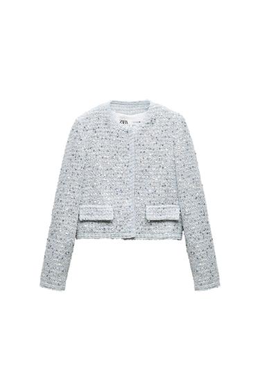 Light gray textured jacket with front pockets and hidden closure. Visible interior label with Zara logo. White background.