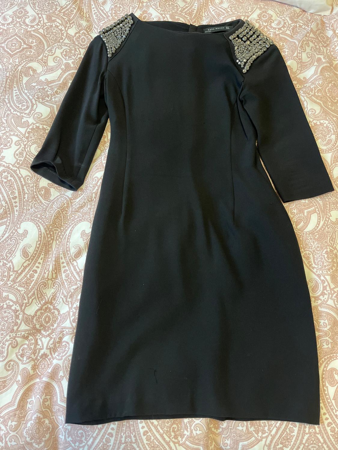 Front view of a black dress with three-quarter sleeves and shoulders decorated with rhinestones.