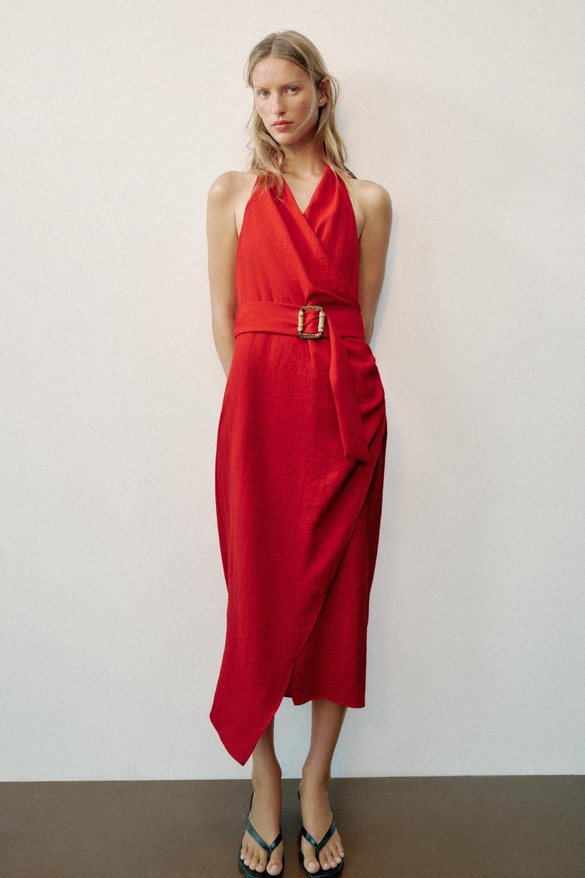 Red midi wrap dress outfit with a halter neck, sleeveless, square buckle belt, asymmetrical hem, and black sandals.