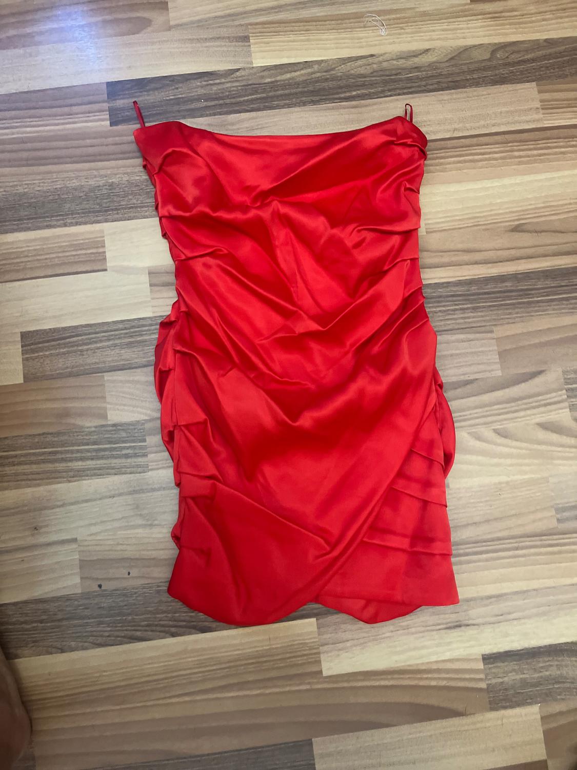 Red dress draped over a wooden floor with brown and beige tones.