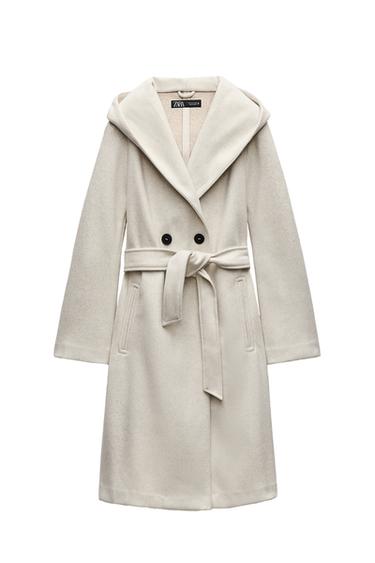 Front view of a white coat with belt, large lapels, and side pockets.