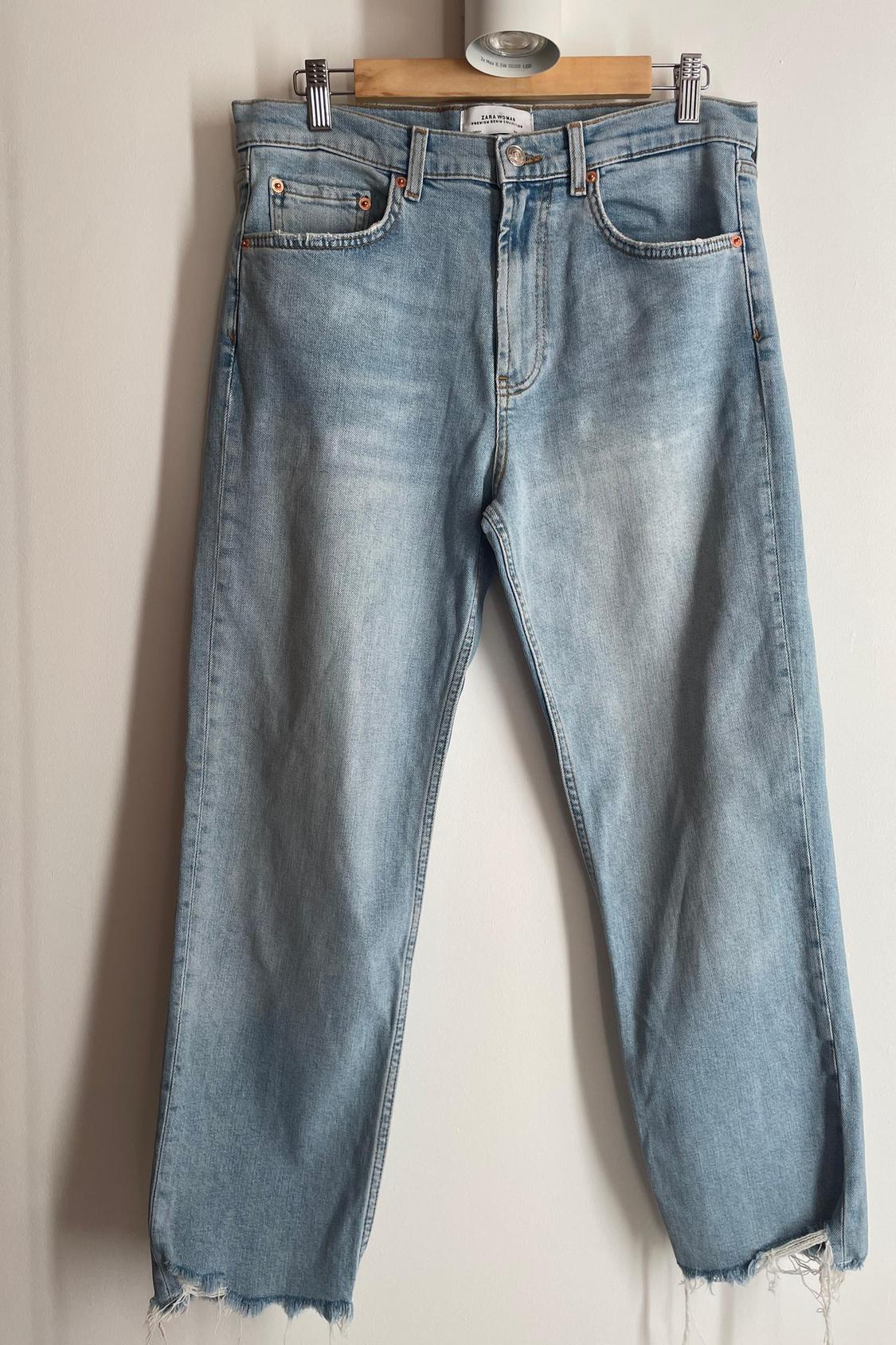 Front view of blue jeans with front pockets and frayed hems.