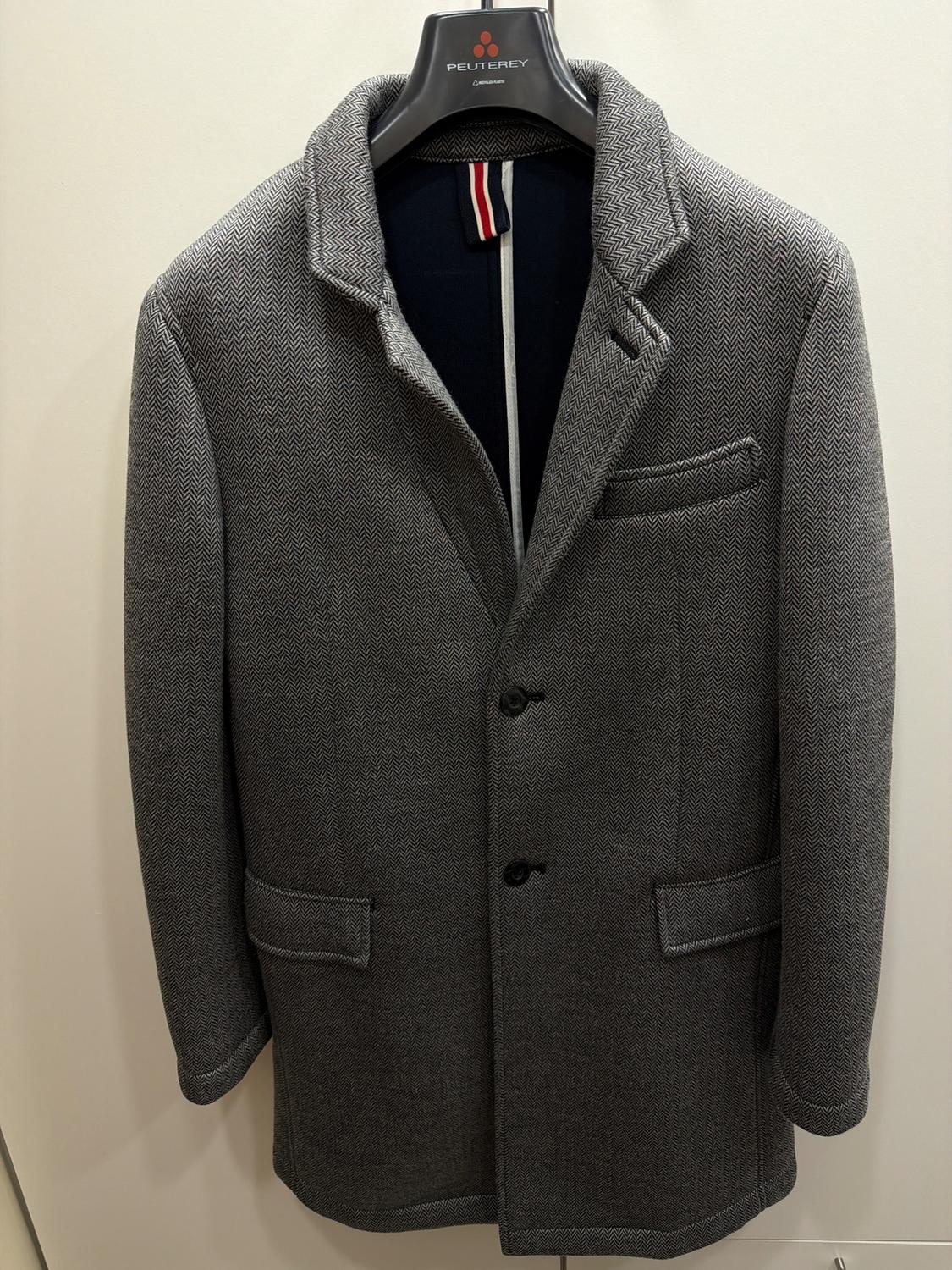 Grey herringbone pattern coat hanging on a Peuterey hanger. It has lapels, two buttons, and front pockets.