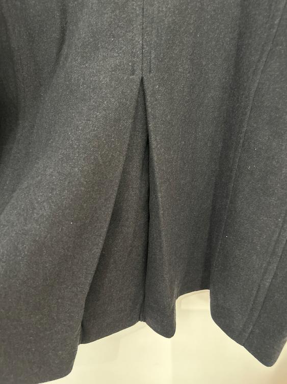 Dark grey fabric with visible pleats in a garment design. Light background.
