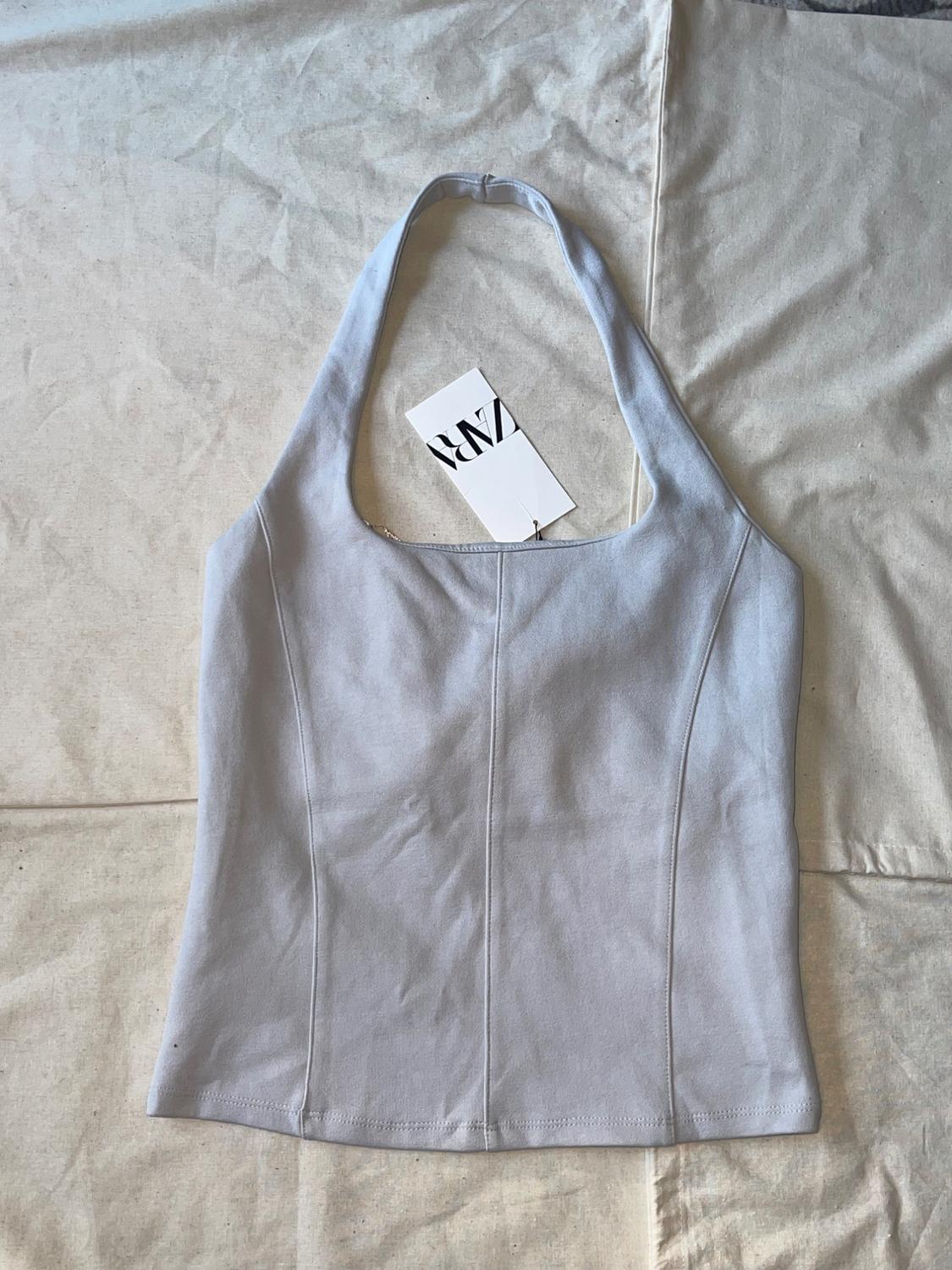 Light gray halter neck top with vertical seams on a crinkled fabric background. Label with the text ZARA.