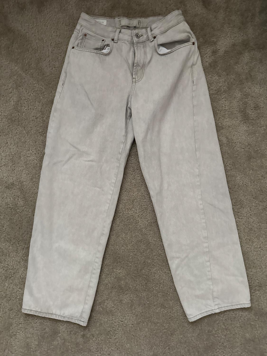 Light grey jeans on a beige rug, with visible front and back pockets.