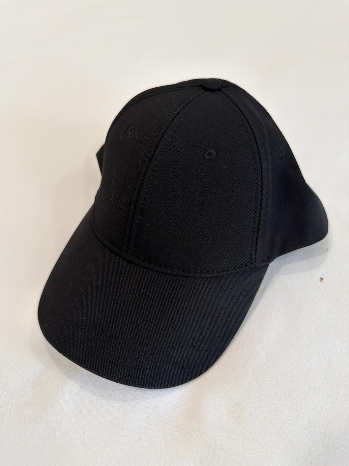 Classic black cap with a curved brim and stitched panels, resting on a white background.