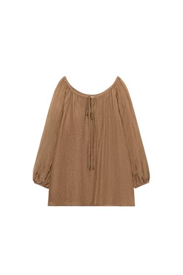 Front view of a toffee blouse with an adjustable straight neckline, long puffed sleeves with elasticated cuffs, and a straight hem.