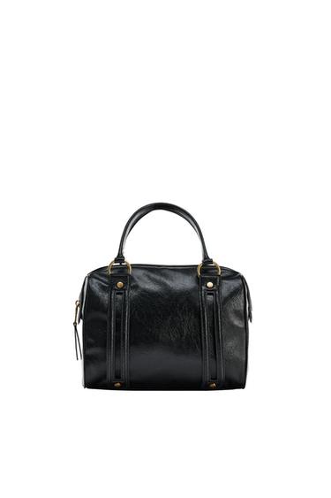 Black handbag with a glossy finish, top handle and gold-tone metallic details on a white background.