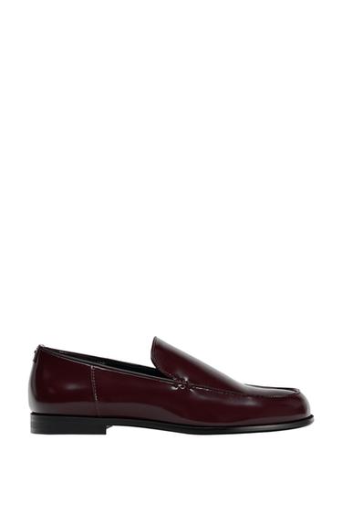 Side view of a burgundy loafer with a polished finish and a black sole.
