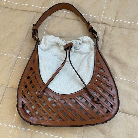 Brown bag with an openwork design and drawstring closure over beige fabric, placed on a beige padded surface.