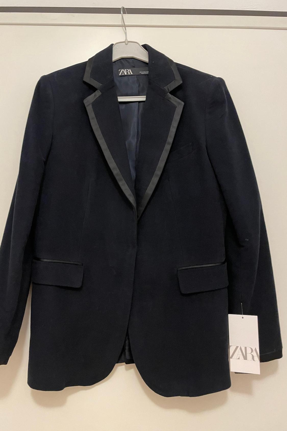 Front view of a black jacket with satin lapels and side flap pockets.