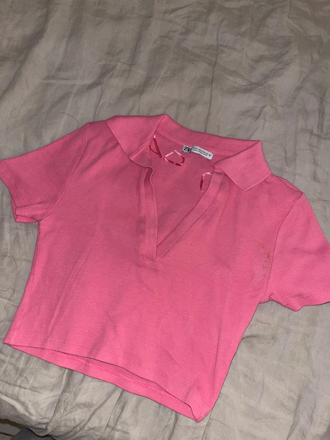 Front view of a pink polo shirt with short sleeves.