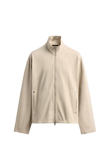 Front view of an sweatshirt with a zip, high neck, long sleeves, and jetted pockets at the hip.