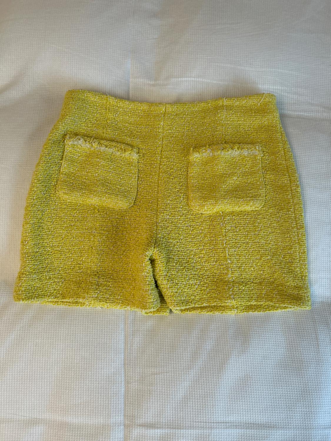 Rear view of yellow shorts with square back pockets.