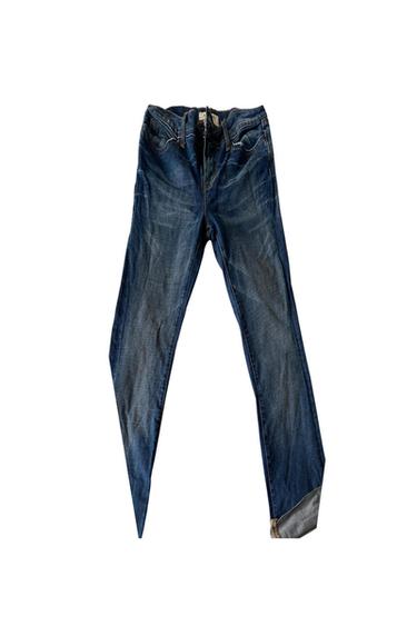 Front view of blue jeans with a distressed effect and a turned-up hem on one leg.
