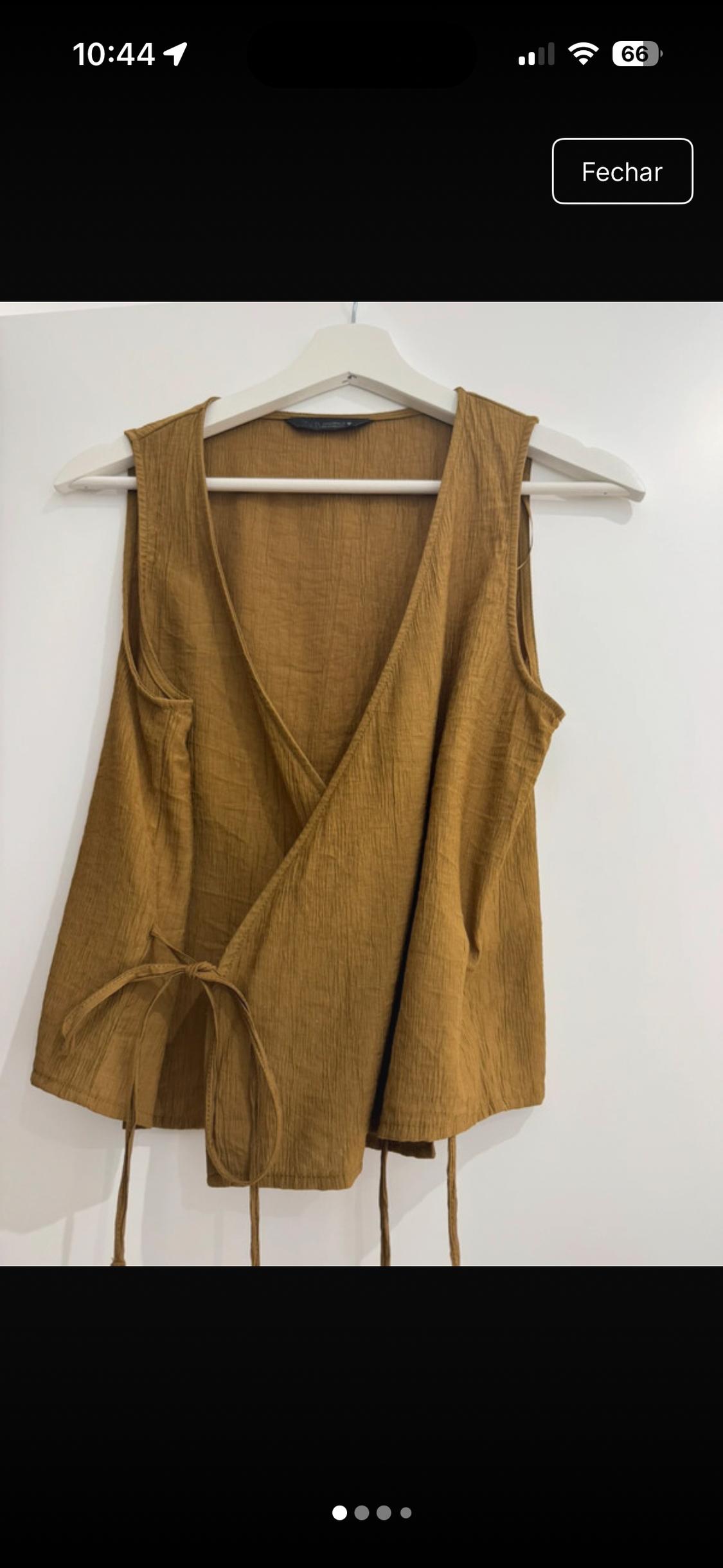 Sleeveless mustard top, crinkled fabric, wrap design with side tie, on a hanger against a white background. Text: 10:44, 66, Close.