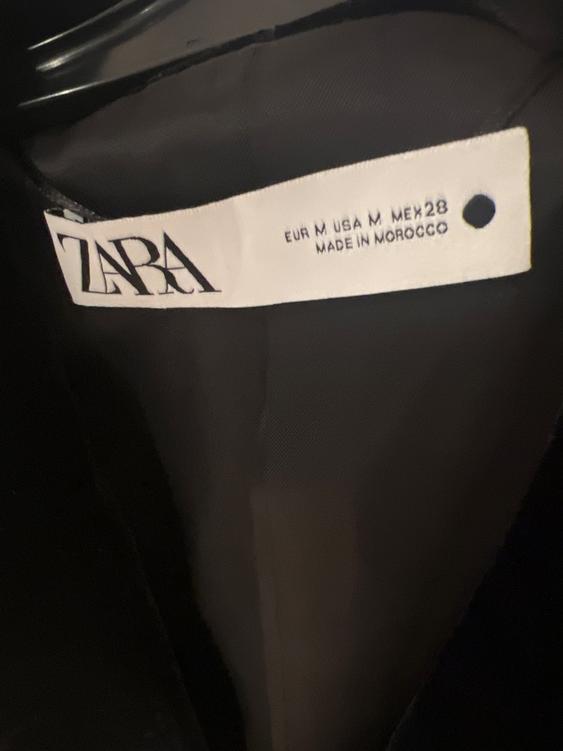 Zara clothing label on a dark background, showing sizes EUR M, USA M, MEX 28, and "Made in Morocco".