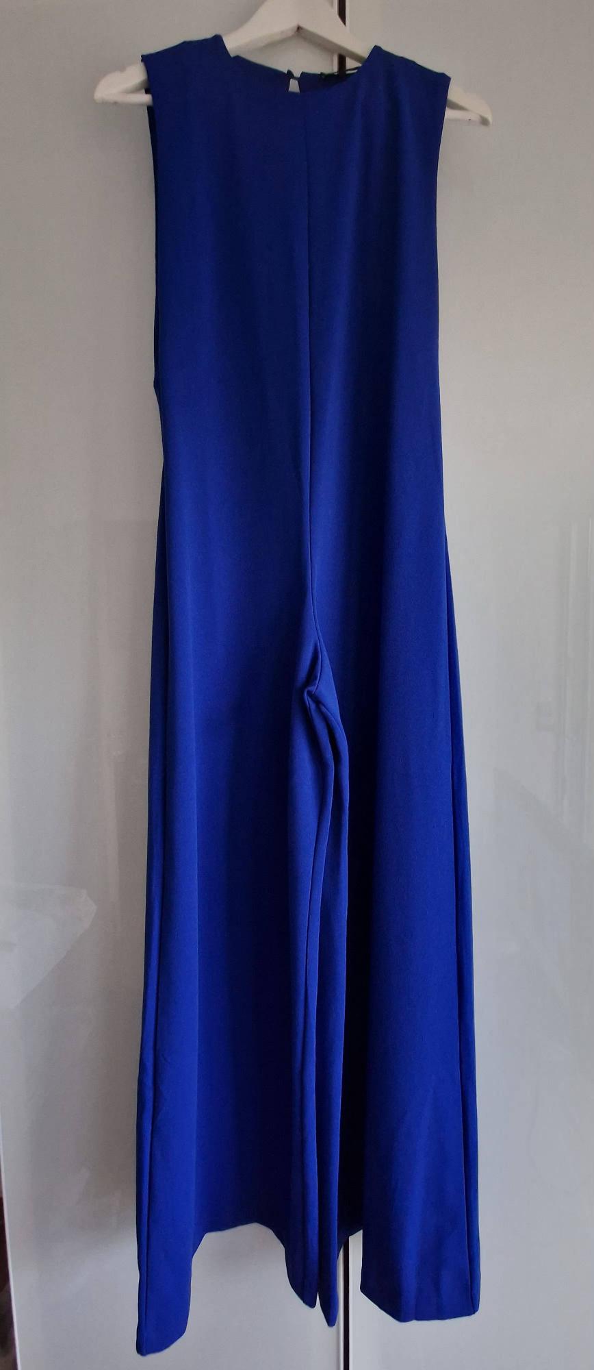 Deep blue sleeveless wide-leg jumpsuit, hanging on a white hanger against a light background.
