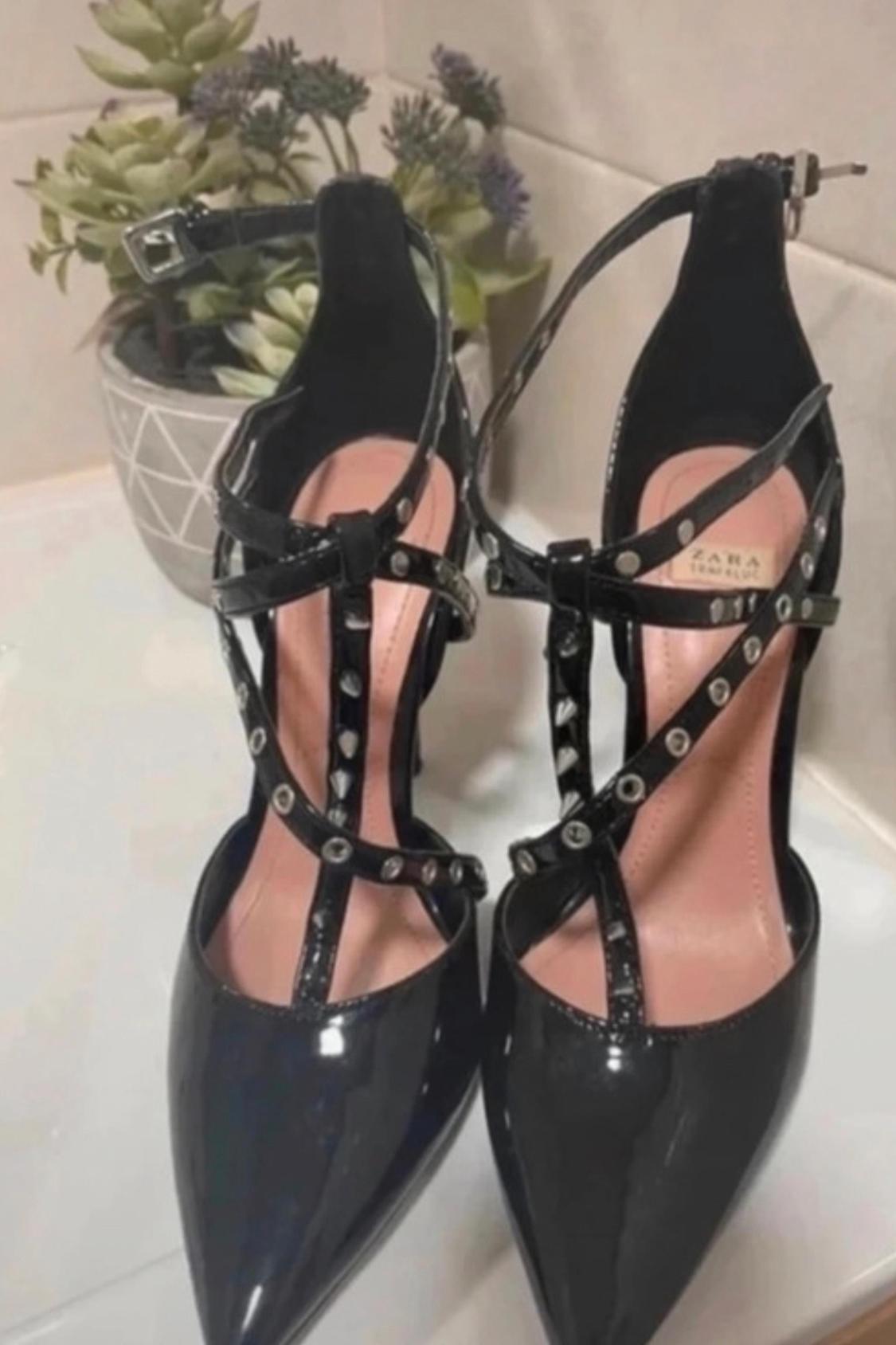 Front view of black pointed-toe shoes with straps and silver studs.