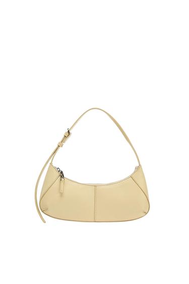 Light yellow crescent-shaped shoulder bag. Features an adjustable strap, zip fastening and visible stitching on a white background.
