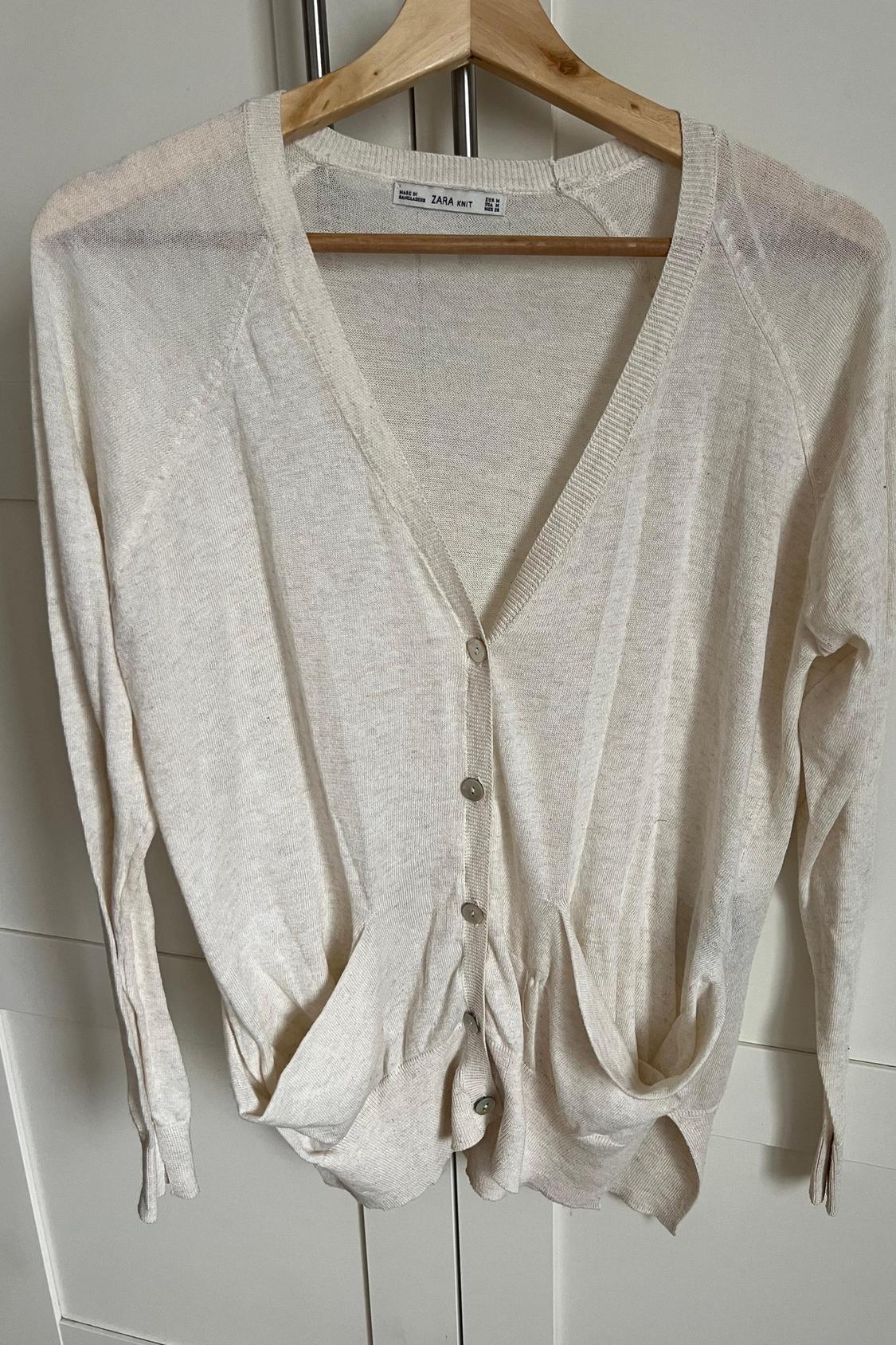 Front view of beige cardigan with buttons and front pockets.