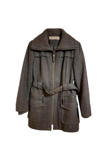 Grey coat with a front zip, ribbed high neck, and belt. Large pockets with a flap and zip closure.