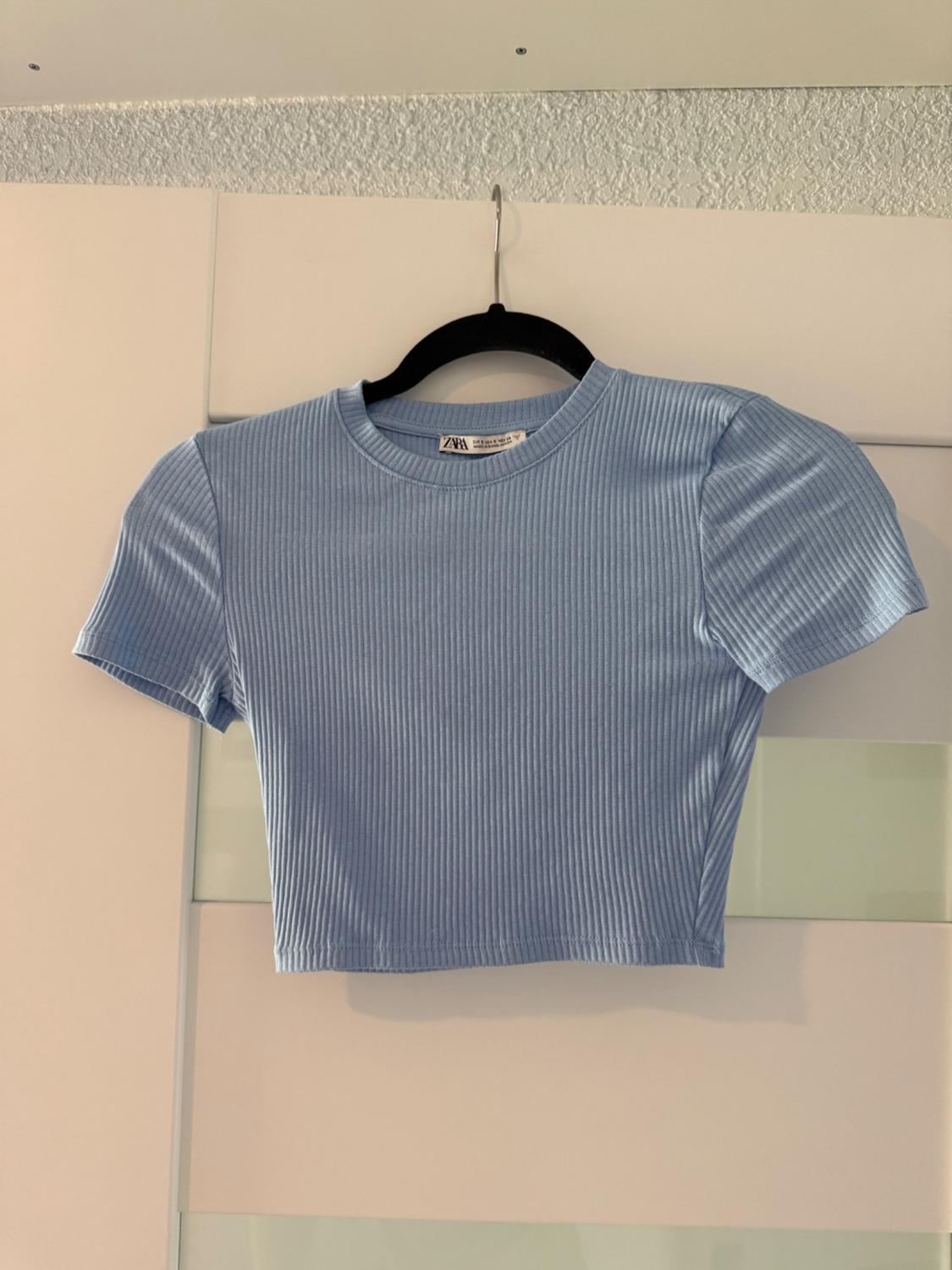 Front view of a light blue cropped t-shirt with short sleeves and a ribbed texture.