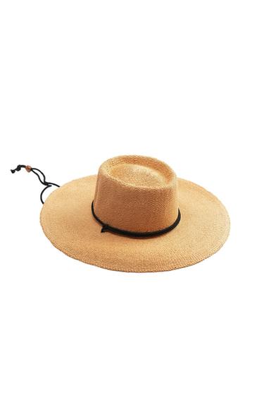 Wide-brimmed straw hat in a natural colour with a black cord on the crown and wooden bead detail, on a white background.