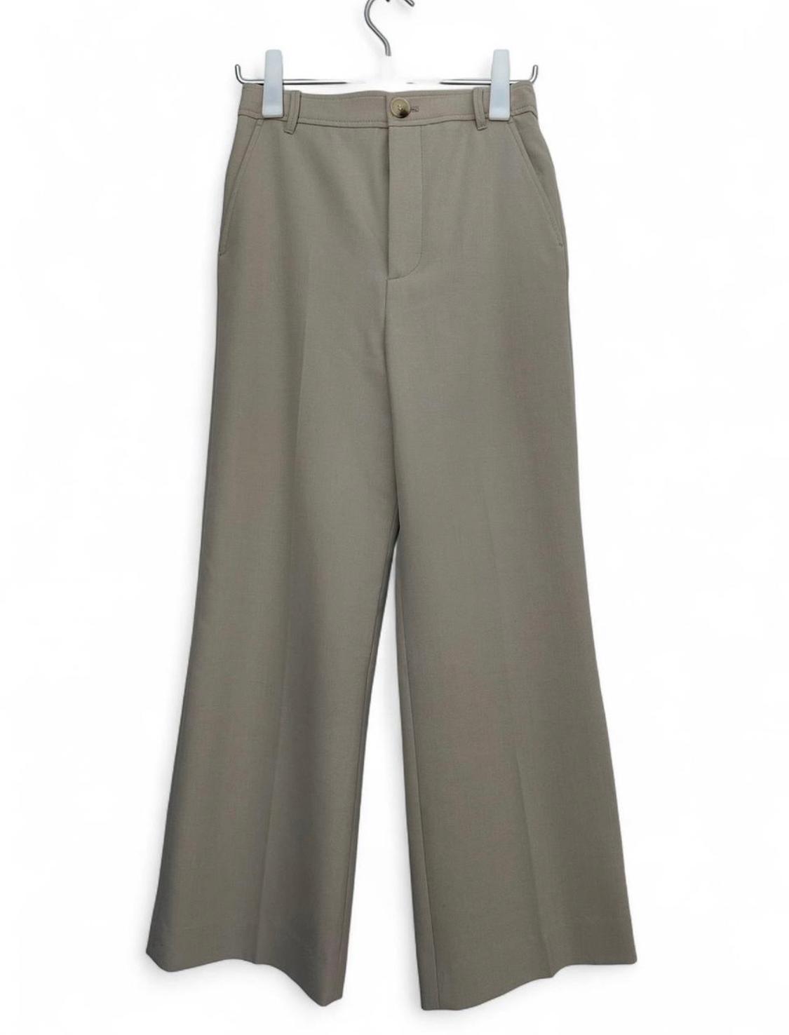 Beige wide-leg trousers with front crease, belt loops, and button closure, hanging on a hanger against a white background.