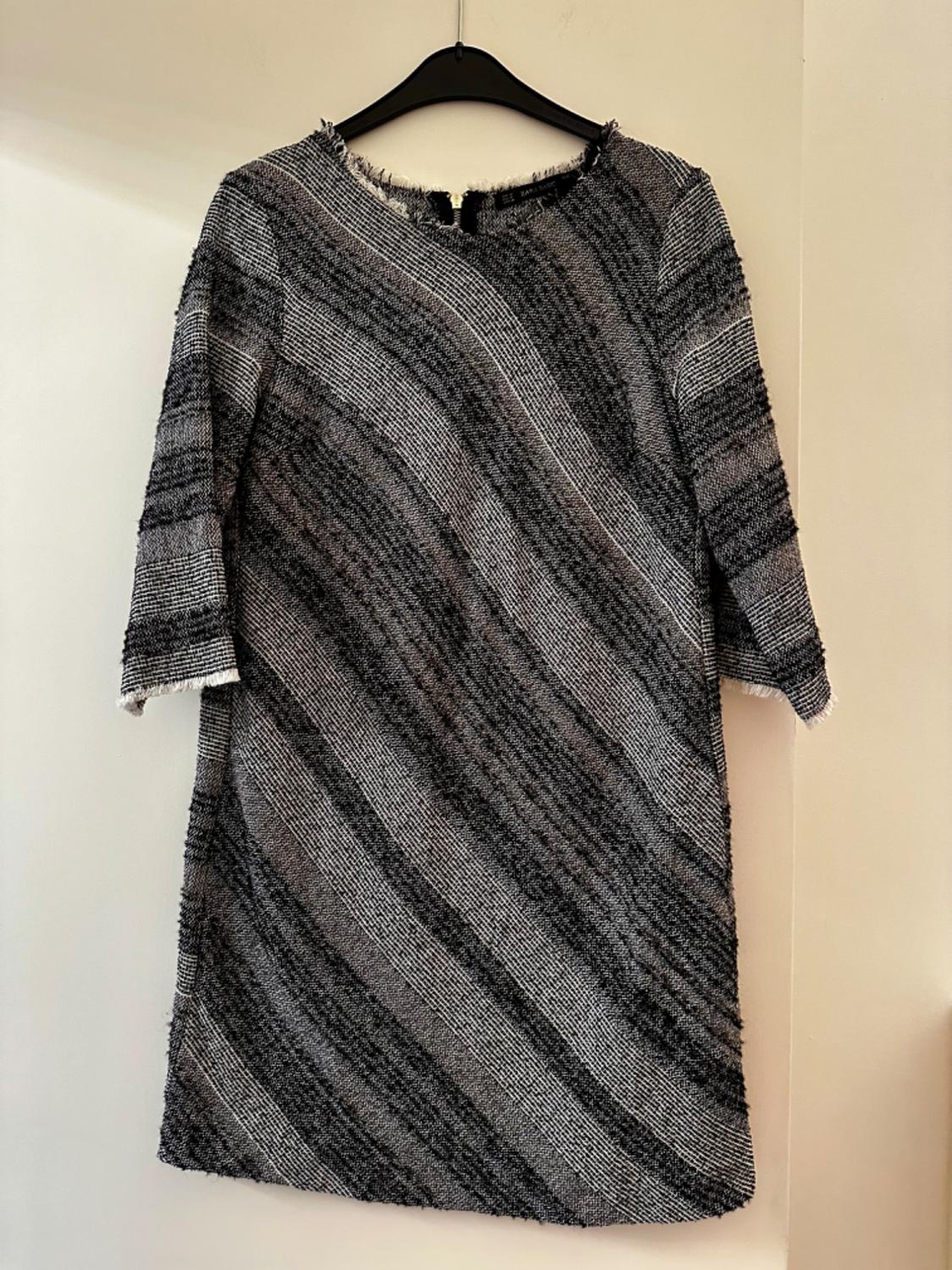 Front view of a grey-toned dress with diagonal stripes, three-quarter sleeves and a round neckline.