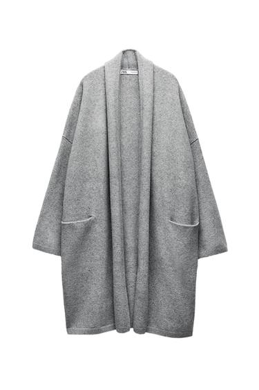 Long grey knit cardigan, open design with two front pockets on a white background. ZARA label at the neck. Relaxed style.