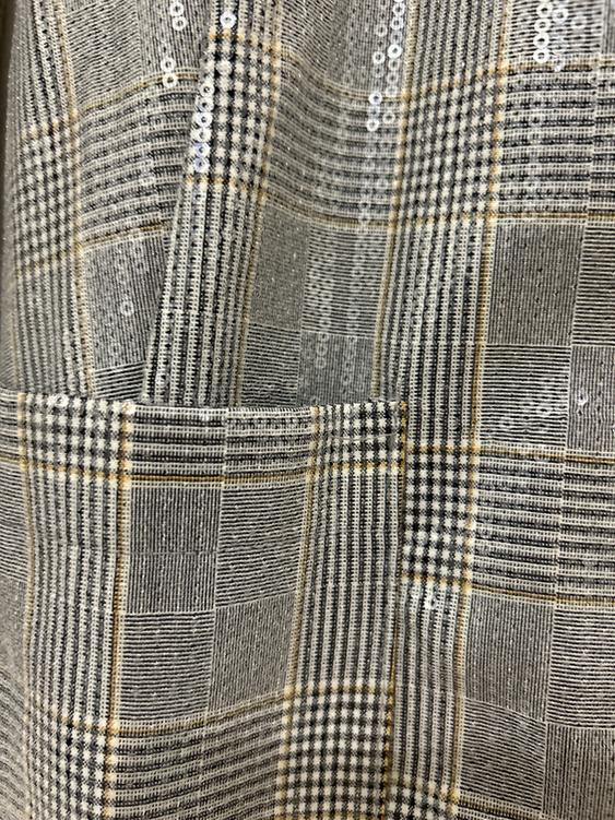Fabric with a checked pattern in shades of grey and beige, with shiny sequin details distributed across the entire surface.