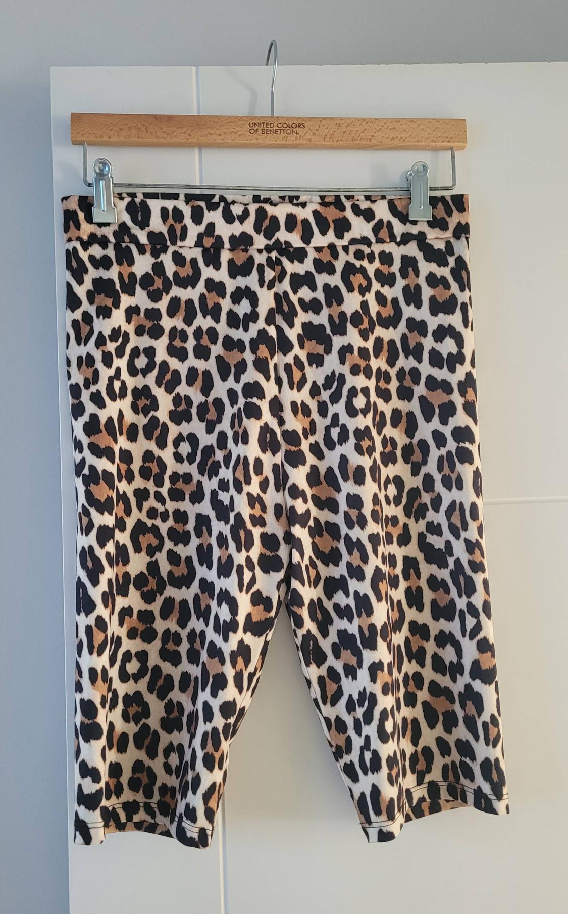 Leopard print shorts hanging on a wooden hanger that reads "United Colors of Benetton".