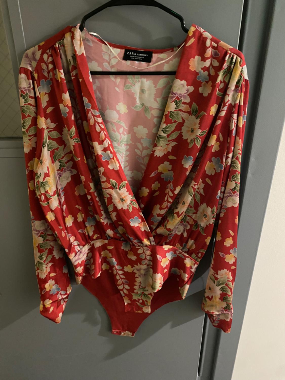 Front view of red bodysuit with floral print and V-neck.