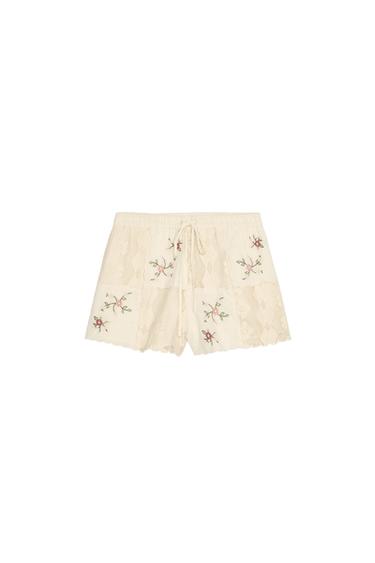 Front view of beige shorts with floral embroidery and elasticated waist