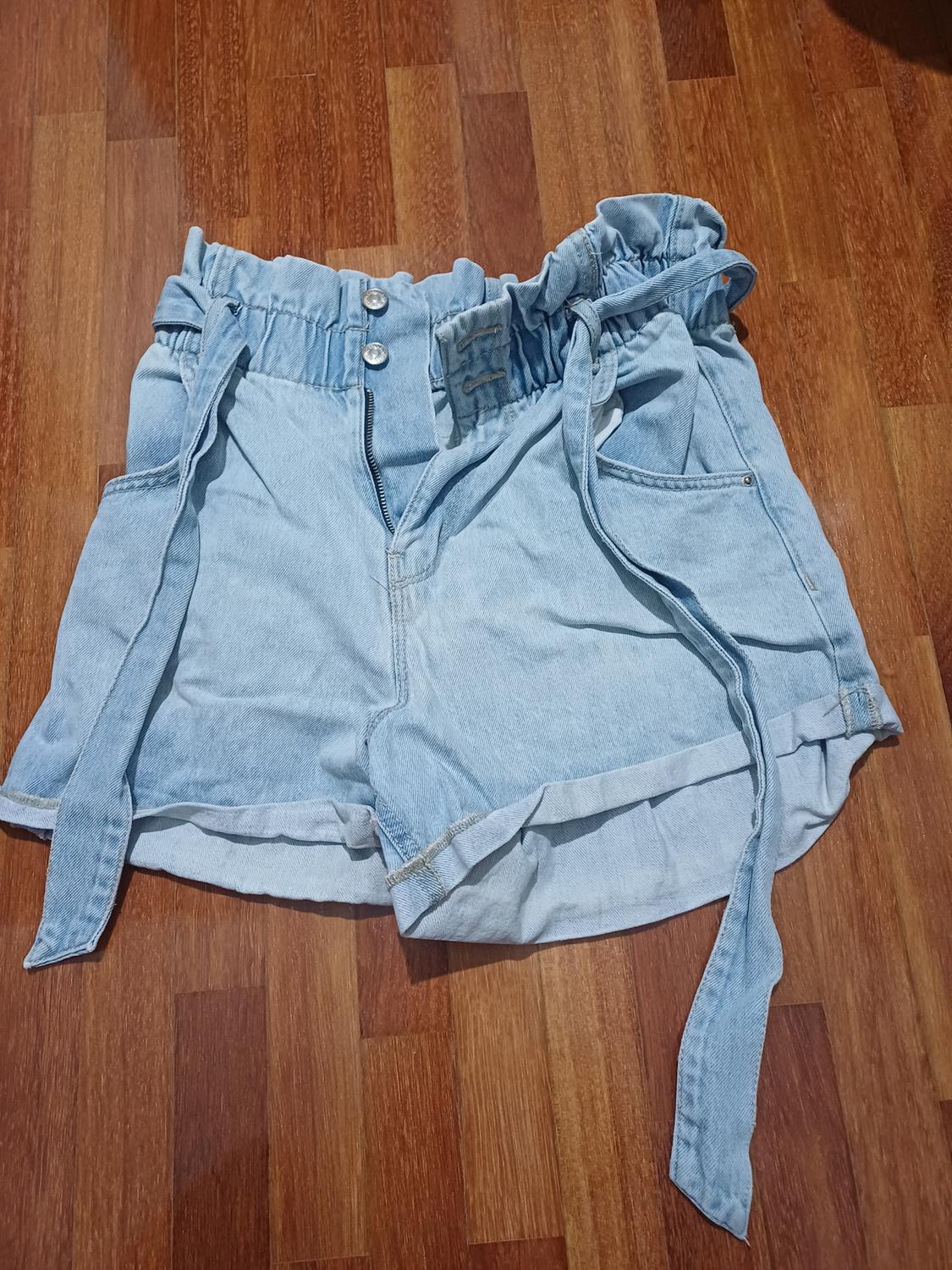 Front view of light blue denim shorts with an adjustable waistband and side pockets.