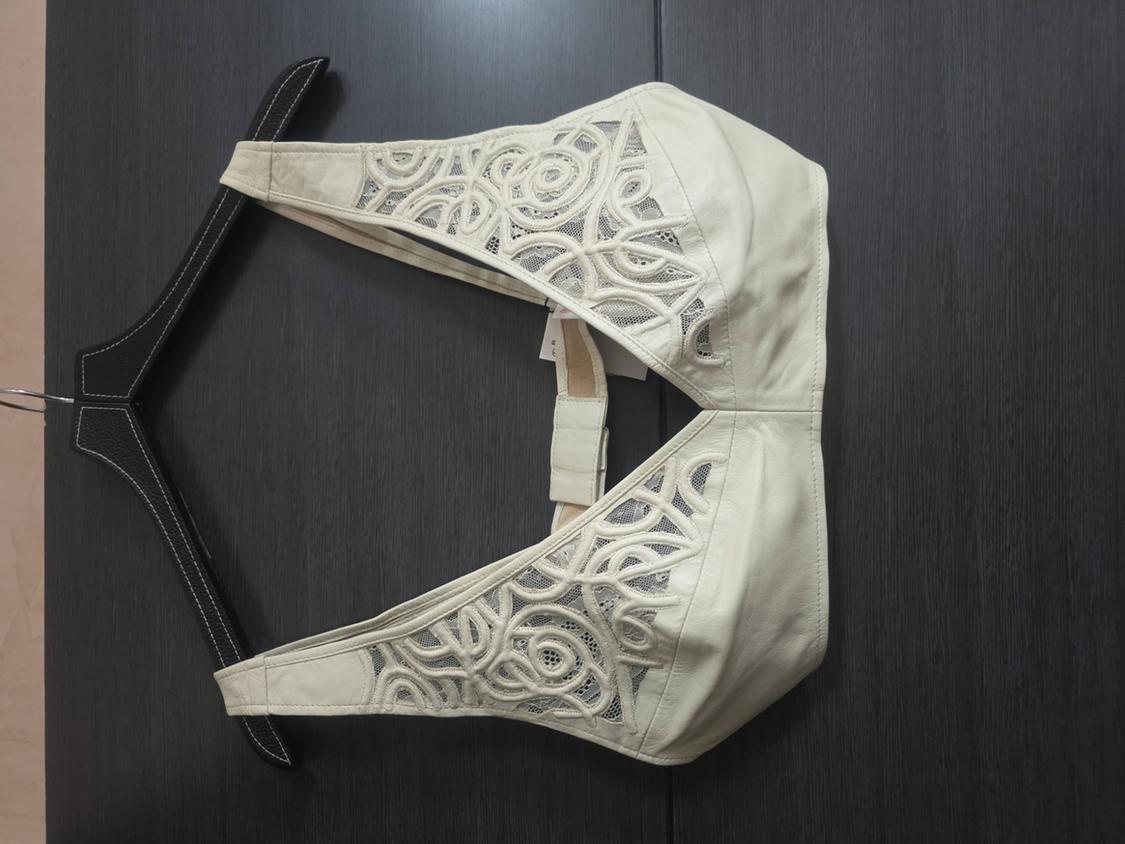 Beige bra with lace details on a black hanger against a dark background. Elegant and modern design.