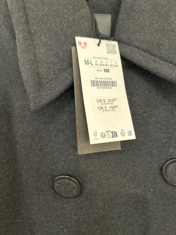 Grey coat label with black buttons. Size M-L, price US $319.00, UK £199.00. Barcode and care symbols visible.