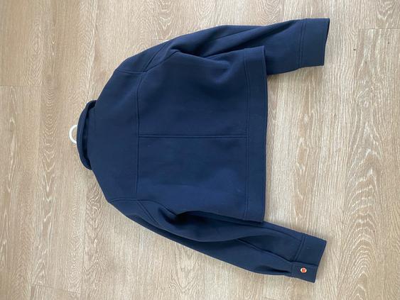 Navy blue long-sleeved jacket seen from behind, on a light wooden floor.