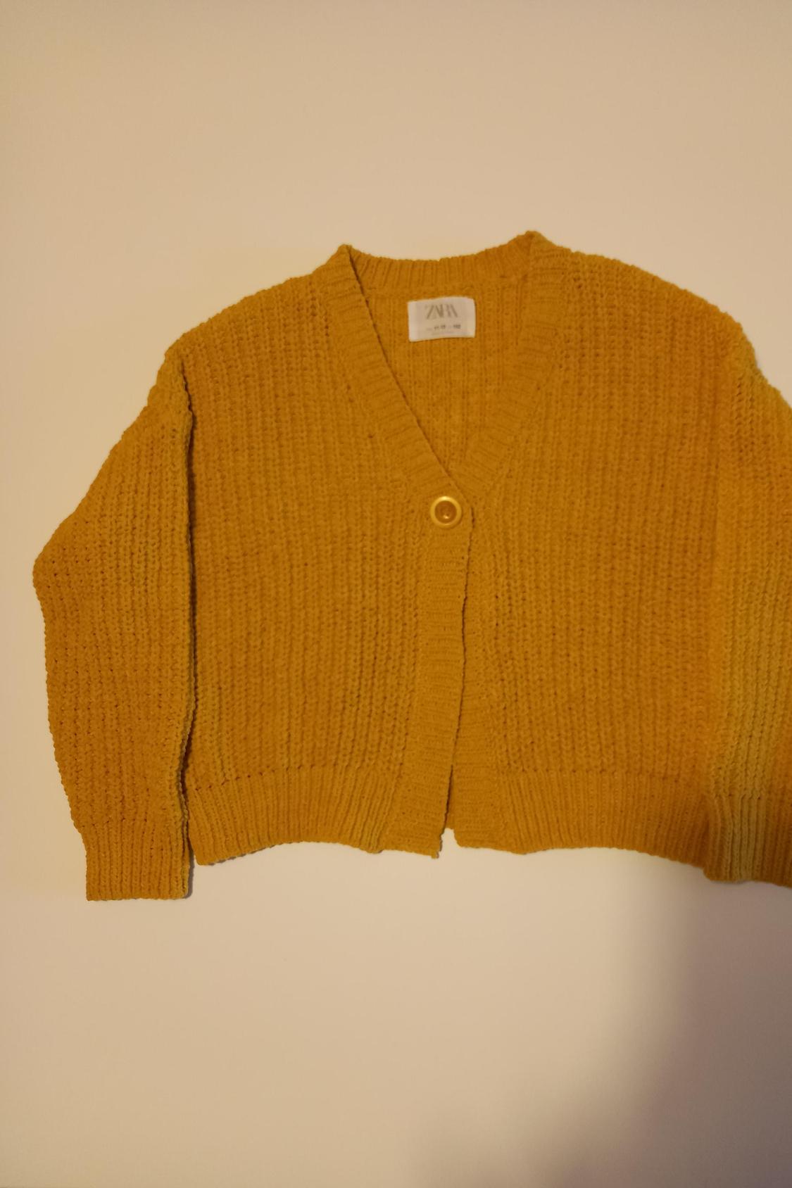Front view of a yellow cardigan with a button and knit texture.