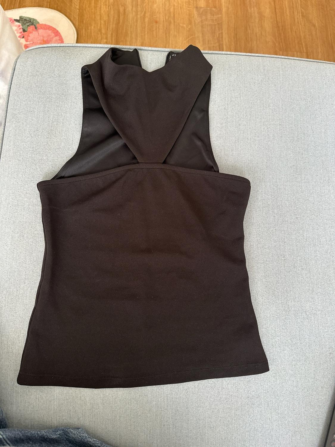 Black racerback top on a light grey sofa. Wooden floor and a floral rug in the background in a relaxed setting.