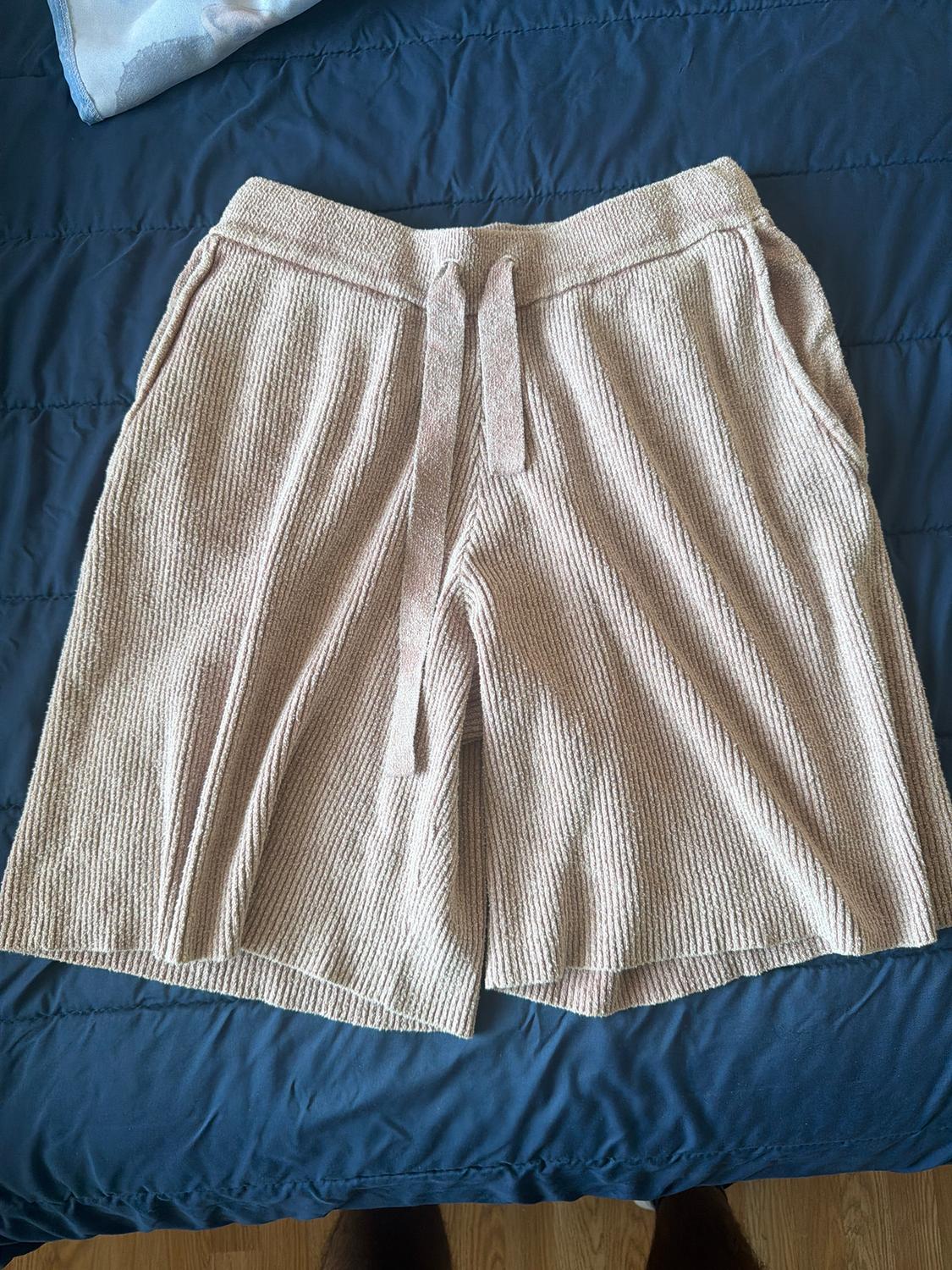 Beige ribbed fabric shorts with a drawstring waist, on a blue bedspread.