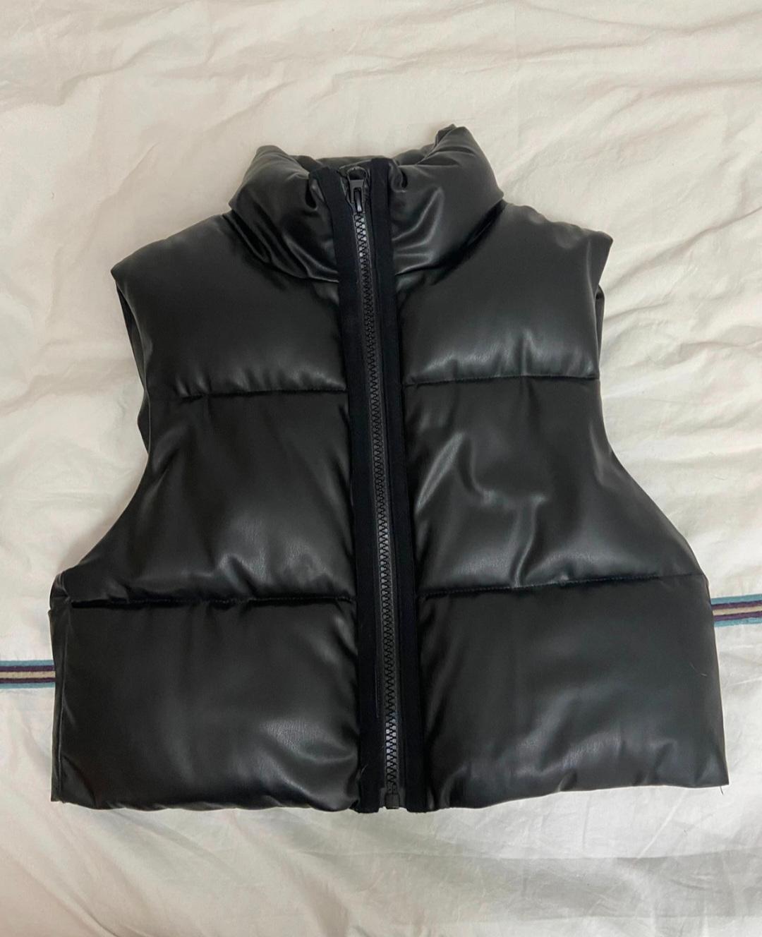 Black padded gilet with front zip, on a white surface.