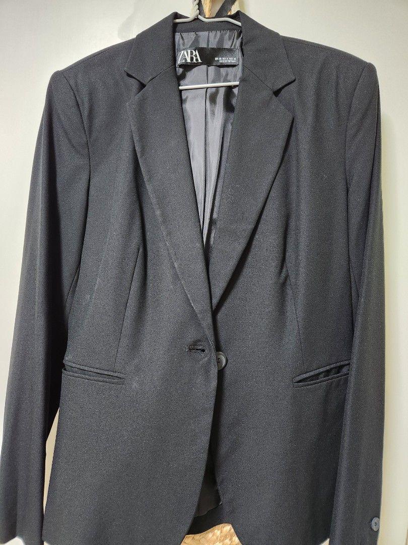 Black suit jacket hanging on a hanger, with classic lapels and one button. Visible label with the ZARA brand.