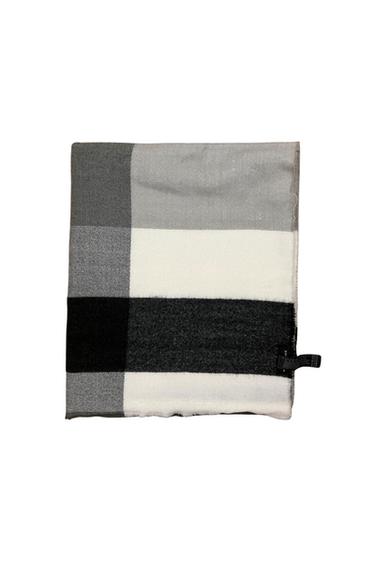 Folded scarf with a large check pattern in black, white, and grey tones. Features fringed edges and a black label on the right side.