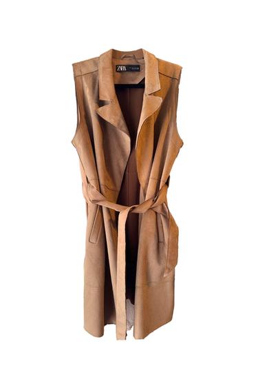 Long camel-coloured waistcoat with a belted waist and lapel collar on a white background. Interior label with the text ZARA.